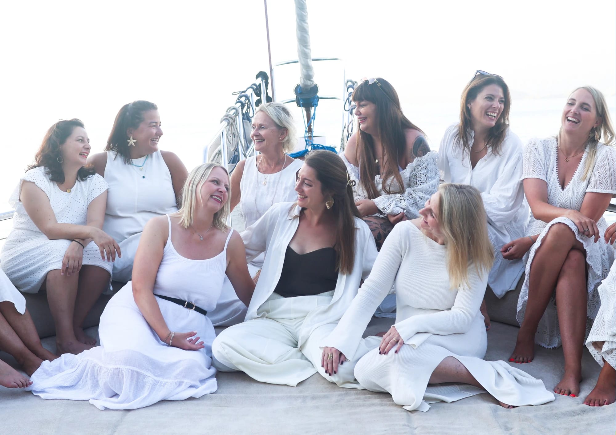 Eine Gruppe Frauen in weißer Kleidung sitzt lachend auf dem Vordeck der Larin Su